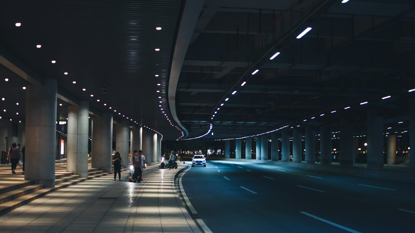 Nächtliche Flughafen-Vorfahrt mit Deckenleuchten und Fahrbahn