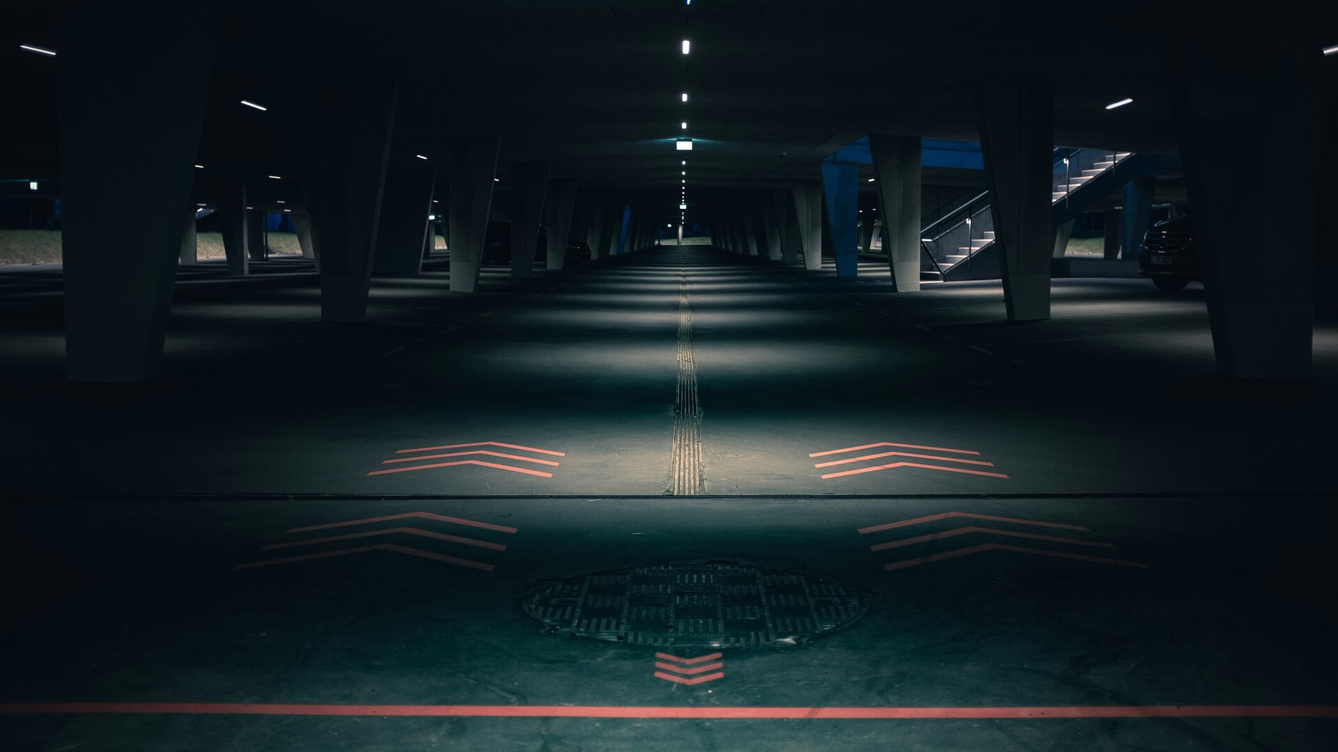 Dunkler symmetrischer Fahrweg in einer nächtlichen Tiefgarage mit kühler Beleuchtung